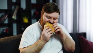 smiling-fat-man-eats-burger-sitting-before-tv-set_8353-5511